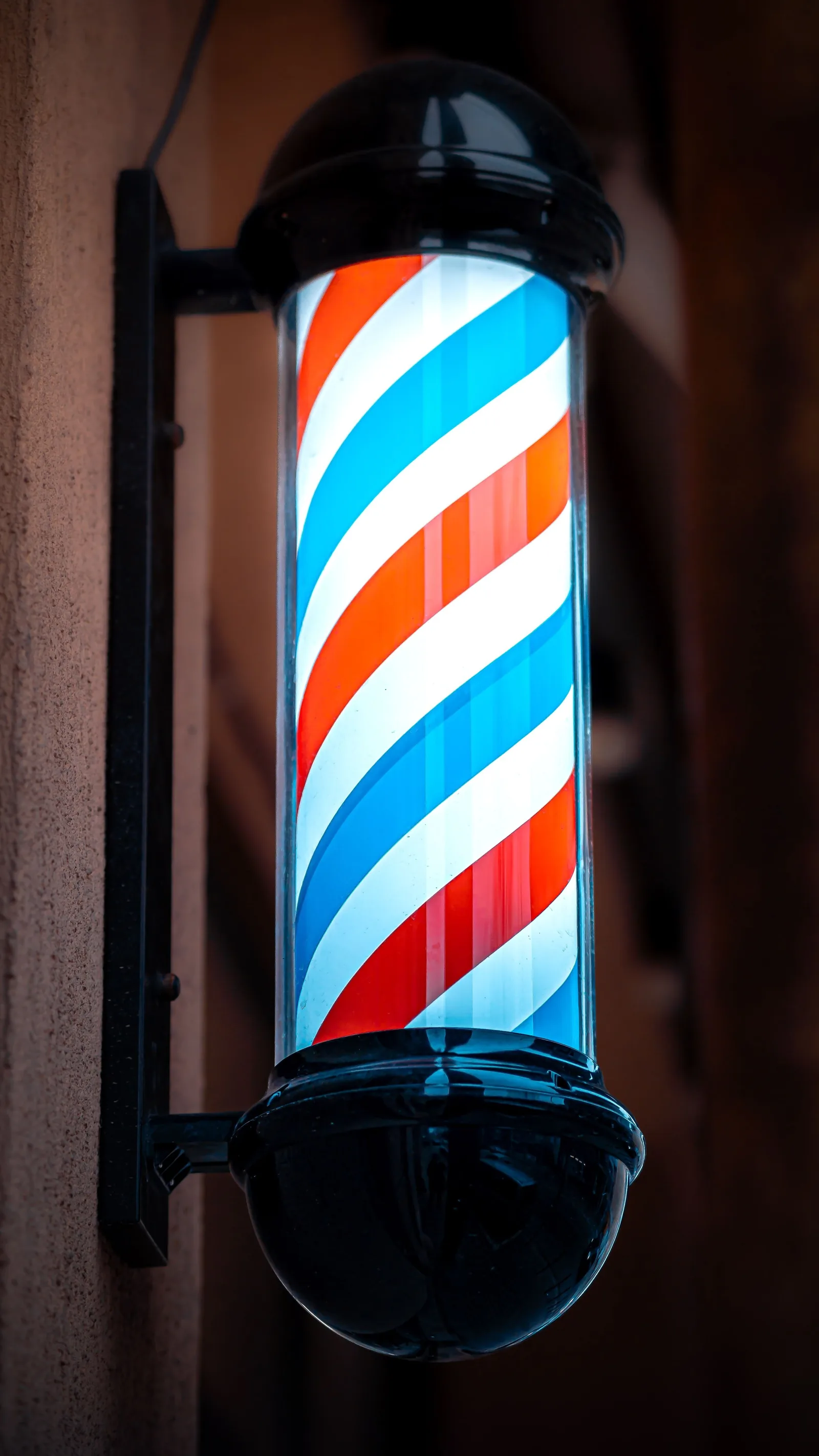 The barber pole outside Pomade, lit at night